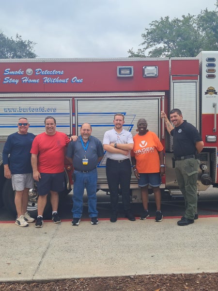 Vaden team and fire department posing in front of a fire truck