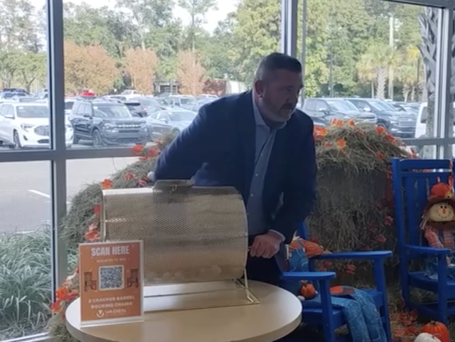 A person standing behind a raffle drum