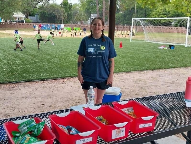 A person standing behind a picnic table with snacks